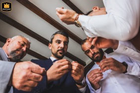 At Domaine de Badine, Gironde, France, the groom and his groomsmen work together to fasten cufflinks, captured in a moment of camaraderie and preparation before the wedding ceremony.